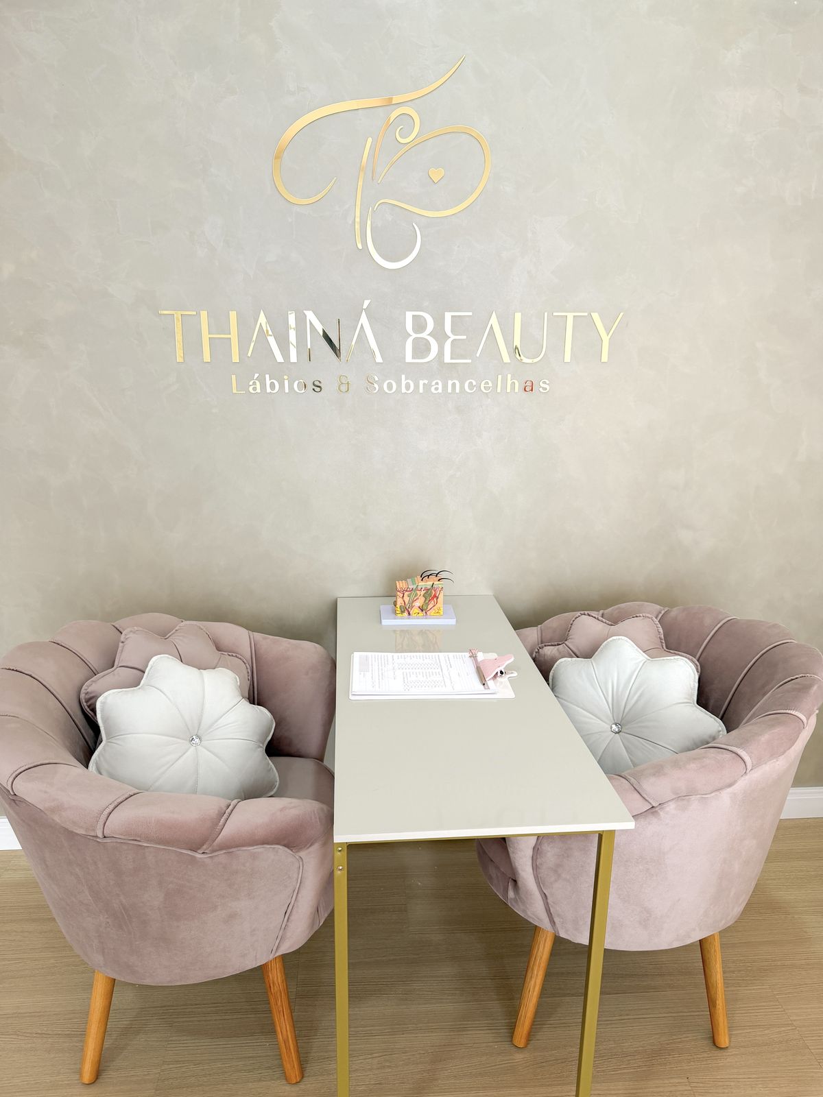 Parede com a marca Thainá Beauty e as poltronas do studio